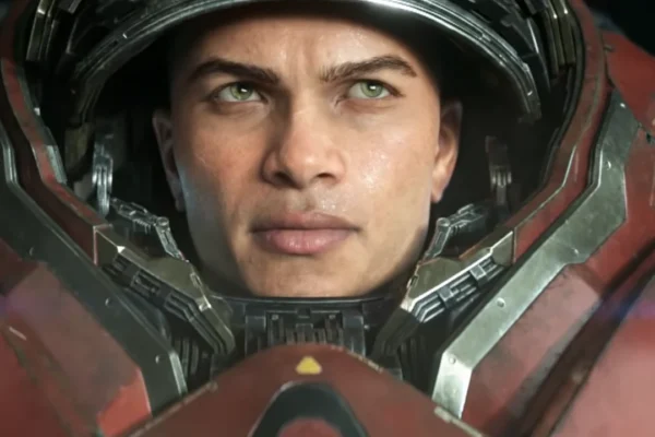 Primer plano de un hombre con ojos verdes y piel morena clara, ataviado con un traje de armadura futurista rojo y gris, reminiscente de un marine Terran de Starcraft. Su mirada seria y decidida ilustra la intensidad del próximo título de la saga.