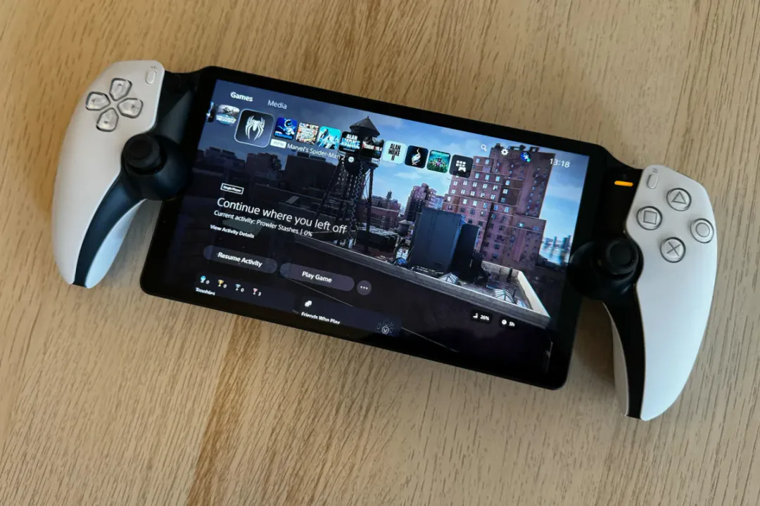 Vista detallada de una consola PlayStation Portal mostrando la interfaz de usuario de PlayStation 5, con el juego Marvel's Spider-Man resaltado. La pantalla muestra la opción 'Continuar donde lo dejaste' y un fondo de rascacielos urbanos, ilustrando la experiencia de juego portátil del ecosistema PS5.