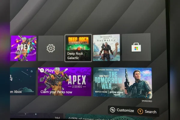 Interfaz del menú principal de Xbox que muestra iconos de juegos junto a un anuncio patrocinado de la película The Tomorrow War, ejemplificando la integración de publicidad en el sistema.