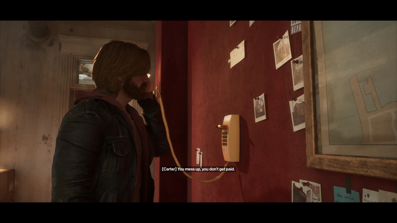 Un personaje del videojuego Samson, Carter, habla por un teléfono de pared en una habitación tenuemente iluminada, con una pared roja decorada con fotografías y un mapa. La escena muestra un momento de diálogo con el subtítulo '[Carter] You mean us, you don't get paid.', ilustrando un aspecto narrativo del juego.